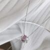 Elegant necklace on reflective surface and fabric.