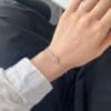 Hand wearing elegant silver bracelet, white sleeve.