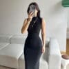 Woman in black dress taking a selfie.