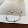 Silver bracelet with green flower accents.
