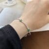 Hand wearing elegant bracelet with green stones.