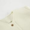 Light-colored textured fabric close-up with button.