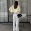 Woman in white outfit holding black bag.