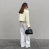 Person in fashionable outfit holding handbag.