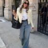 Woman in oversized jeans holding ice cream.
